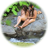 naked couple sit on a rock in the stream